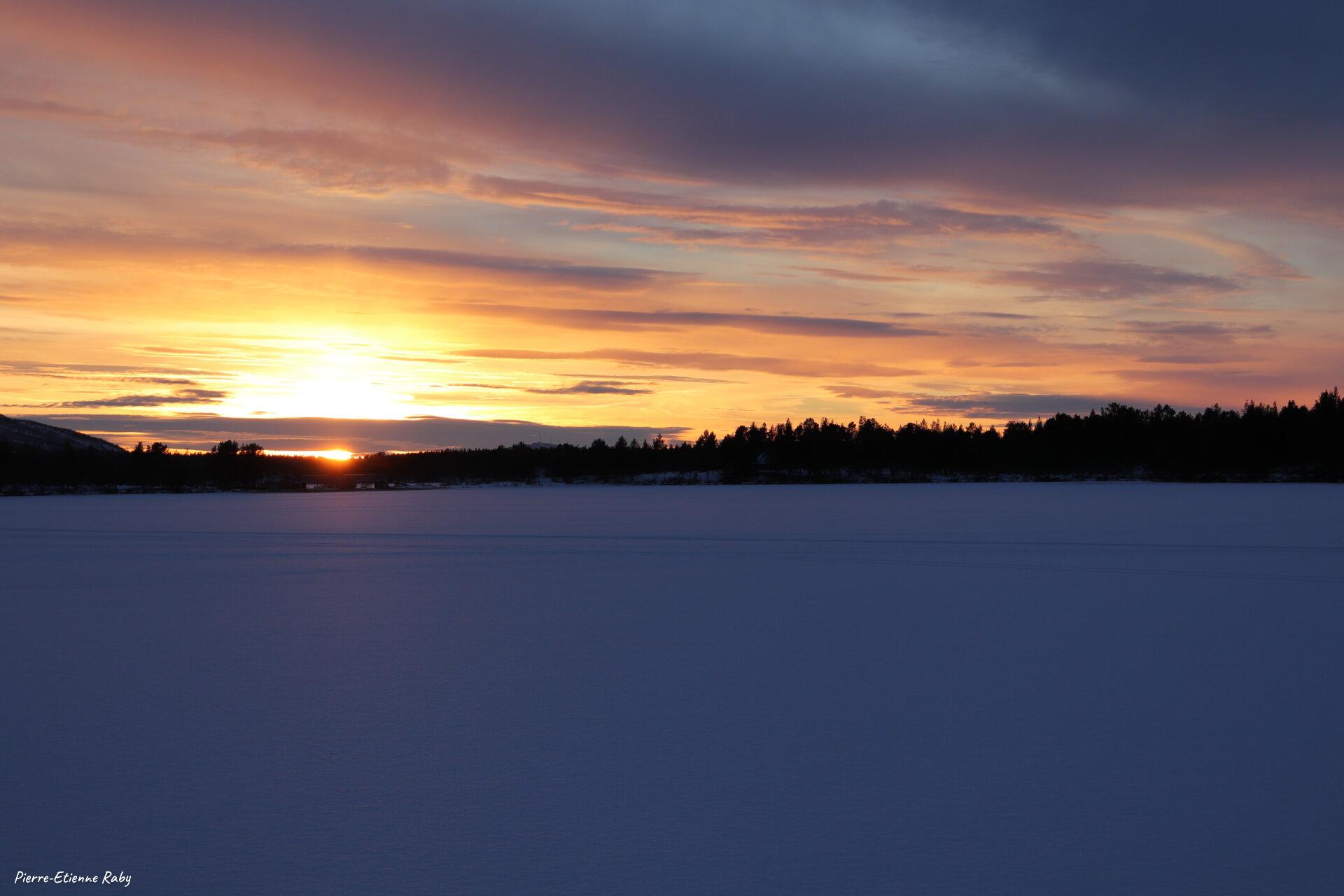 Soleil couchant sur le lac gelé Ruoksujärvi (Suède)